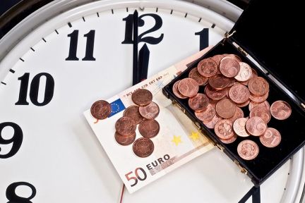 Foto: Geld liegt auf Uhr